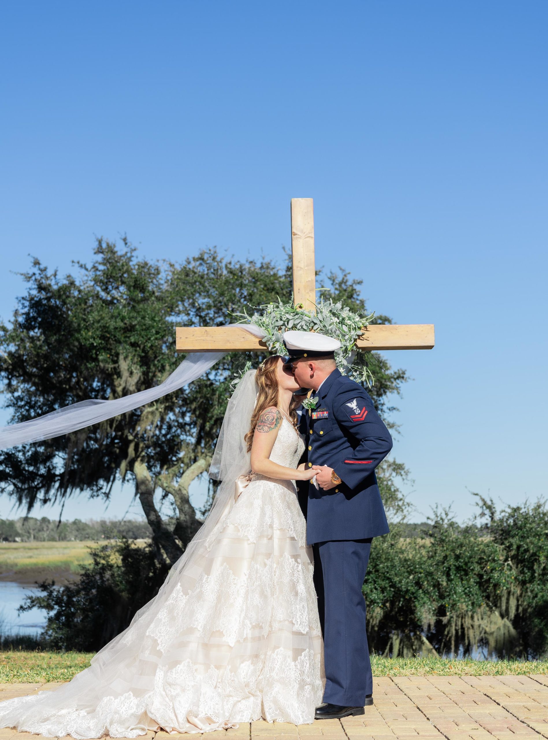 first kiss of married couple in front of a cross at the bluff venue in kingsland georgia