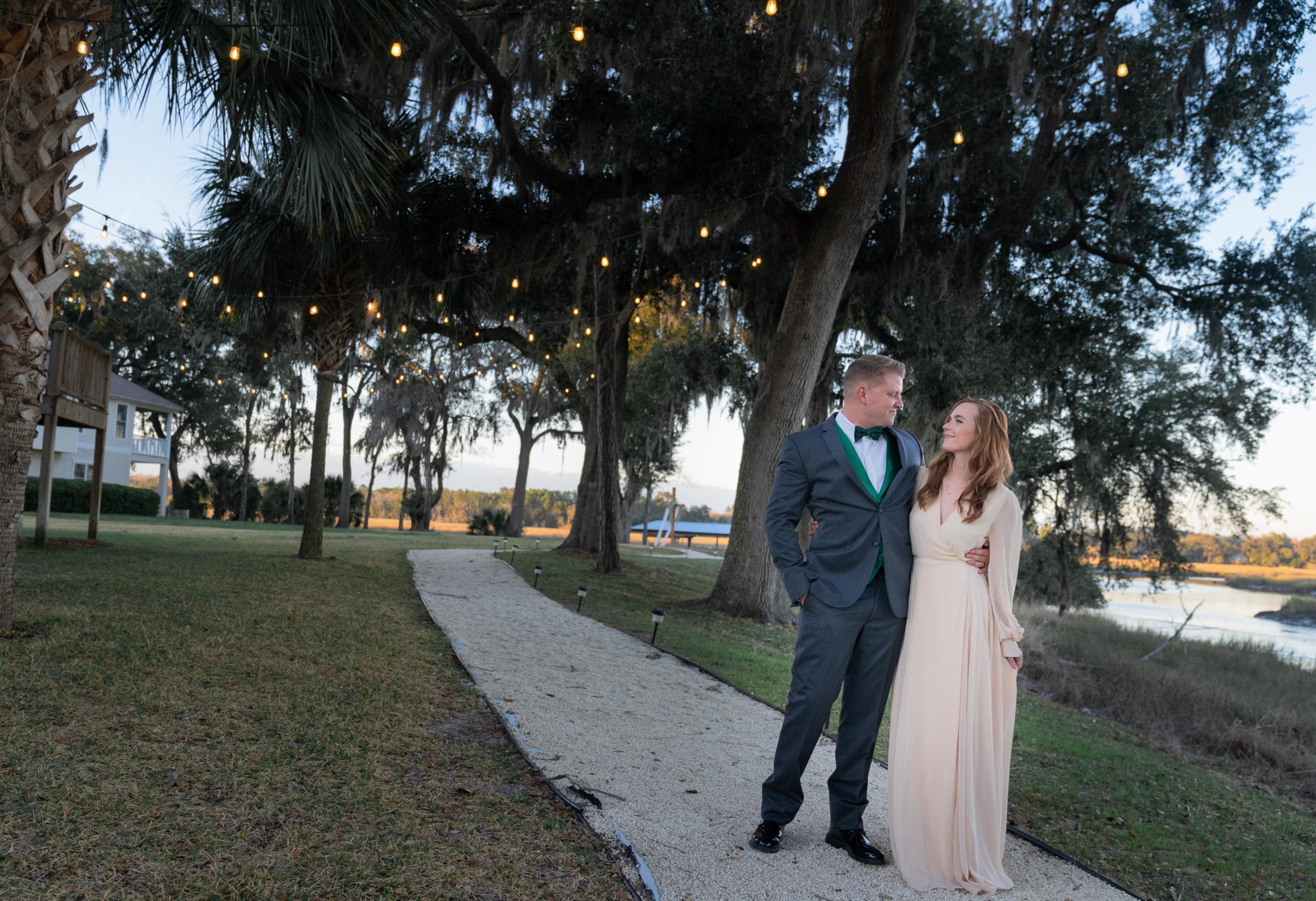 reception photo of couple on walking path under lights and oak trees at The bluff Venue in Kingsland Georgia