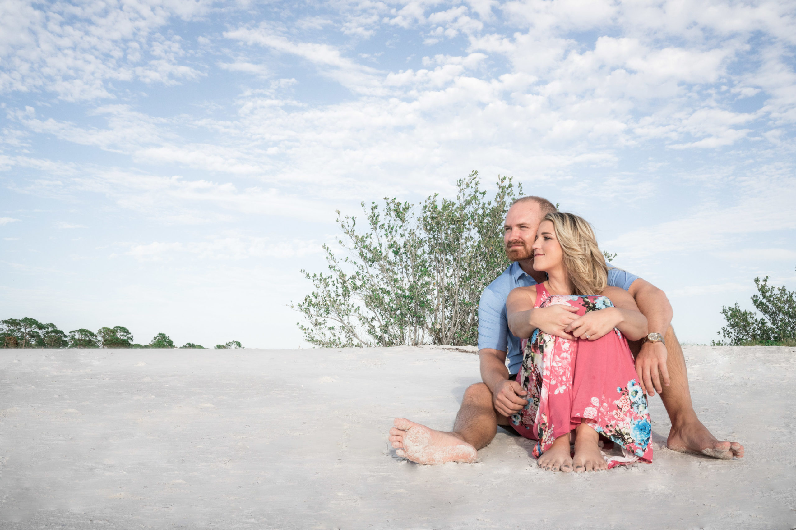 honeymoon island beach in tampa florida engagement session of couple sitting on beach cuddling