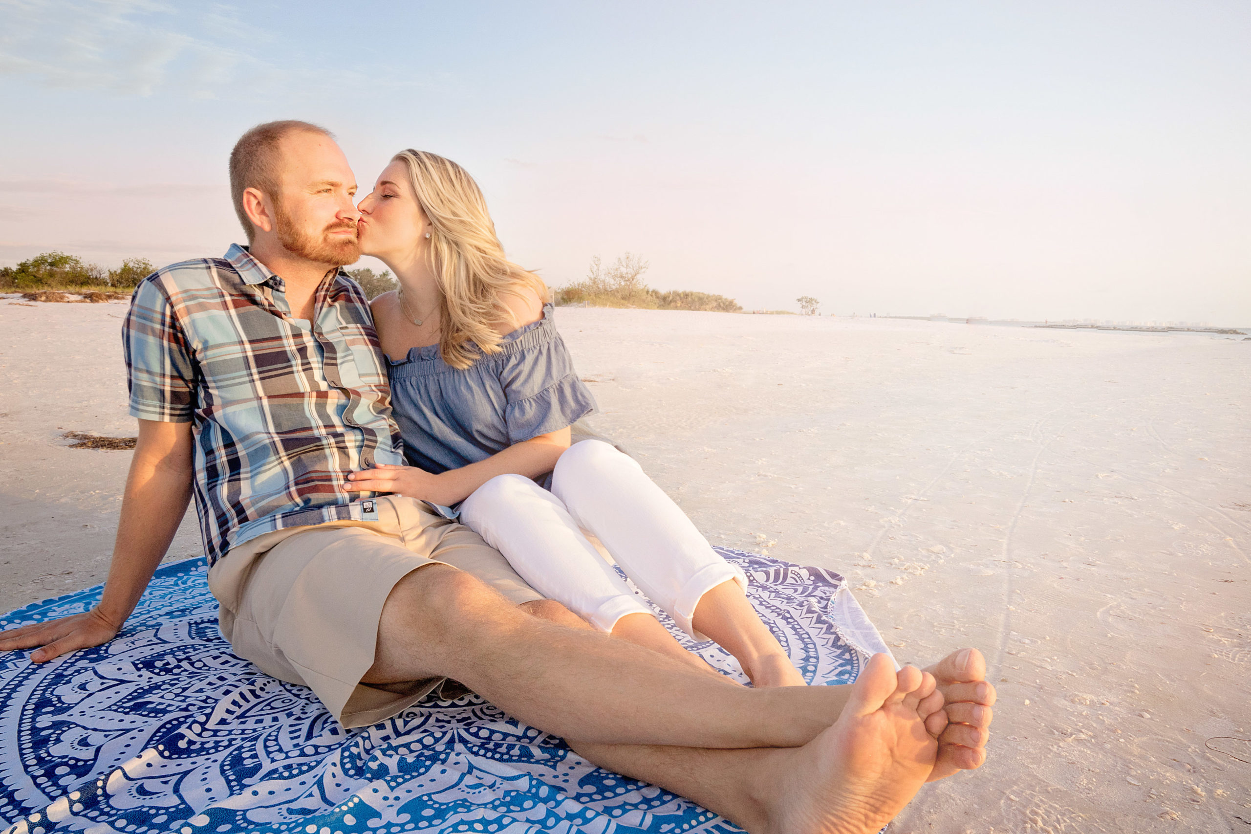 honeymoon island beach in tampa florida engagement session of couple sitting on beach cuddling