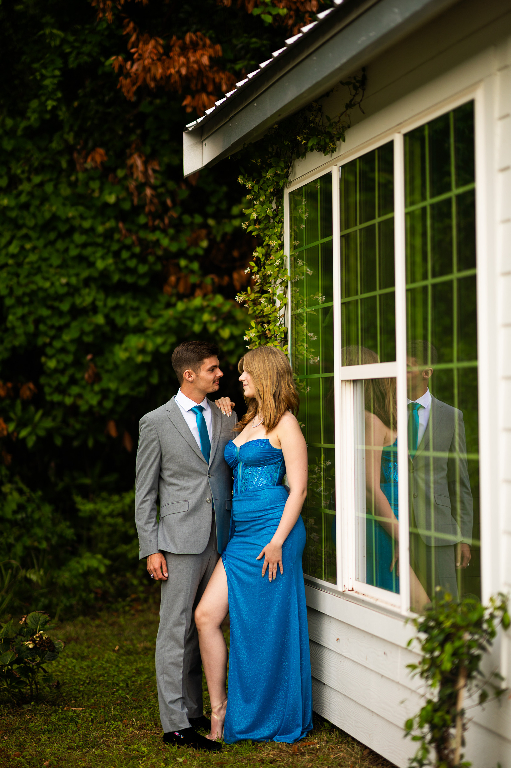 Prom pictures in front on greener and white cottage looking at each other